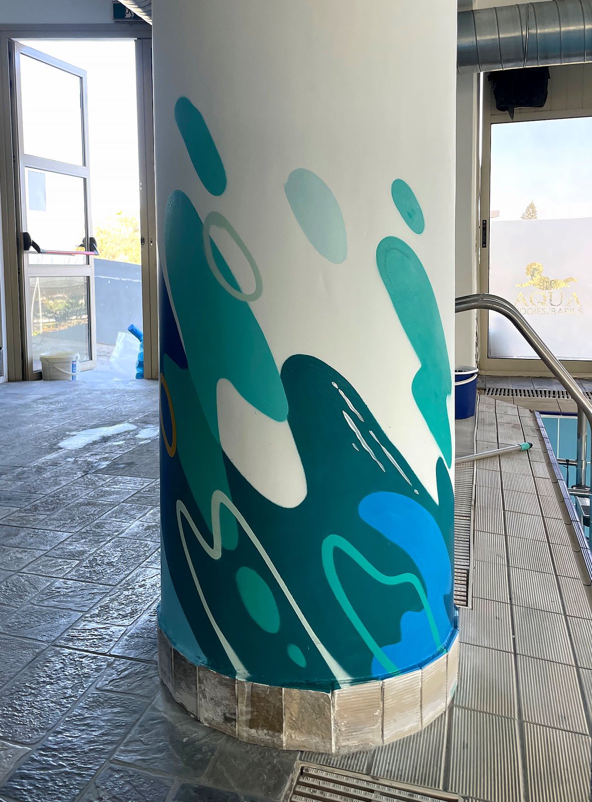 Turquoise wave patterns around a poolside column